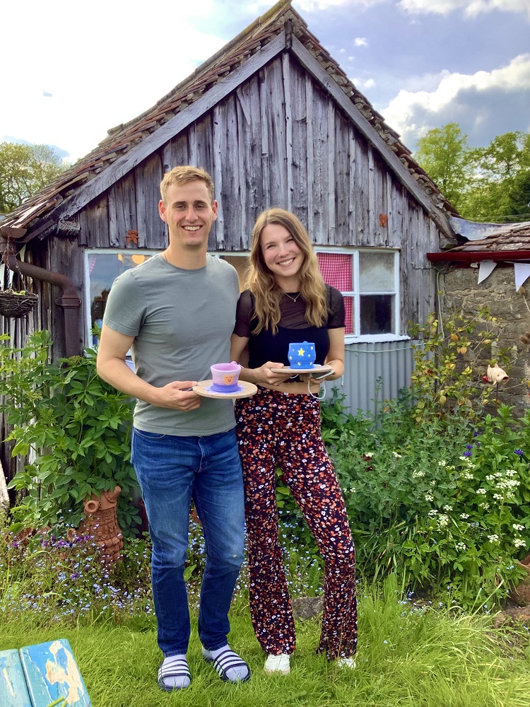 man and woman couple holding pots made on introduction pottery session outside potting shed
