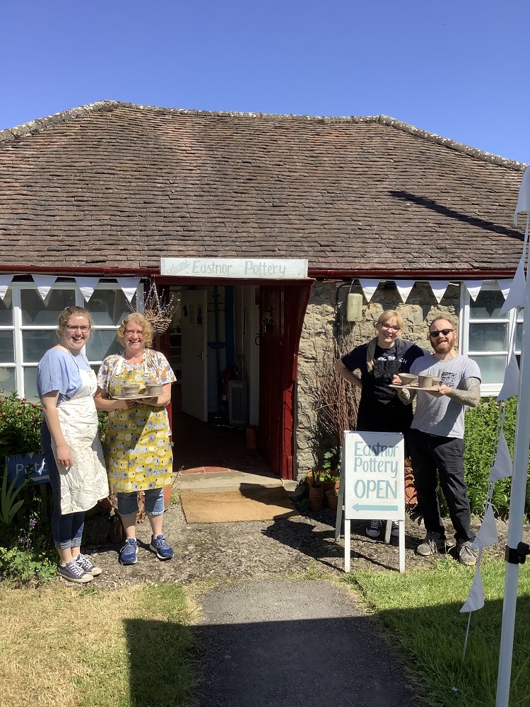 mother and daughter across from man and woman couple standing outside pottery with pots thrown on introductory potters wheel course