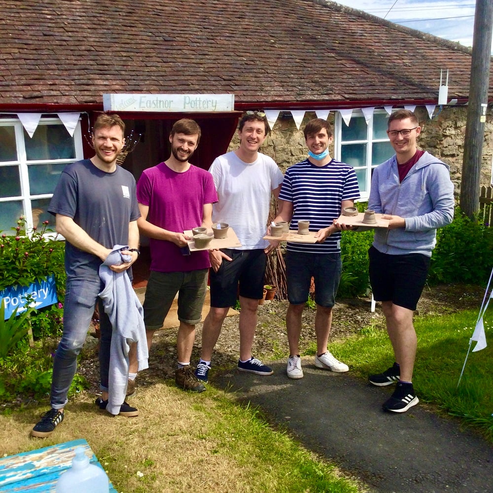 5 men stood outside eastnor pottery hold pots made on introductory session