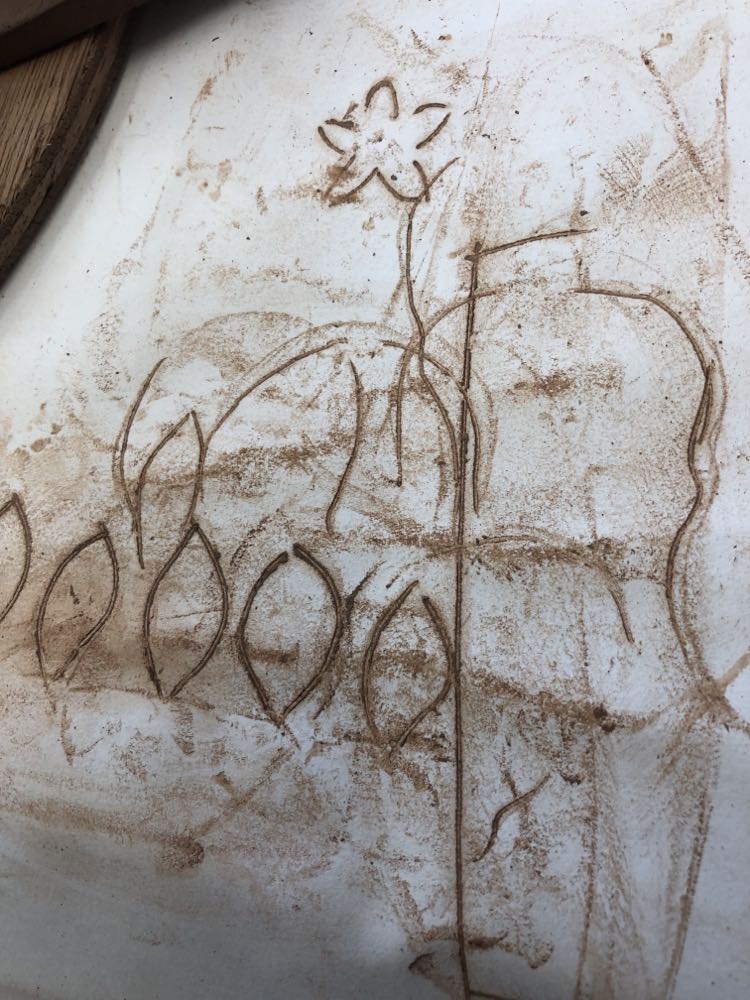 leaf shaped brown lines left on sheets of paper made when cutting different shapes out of flat slabs of clay