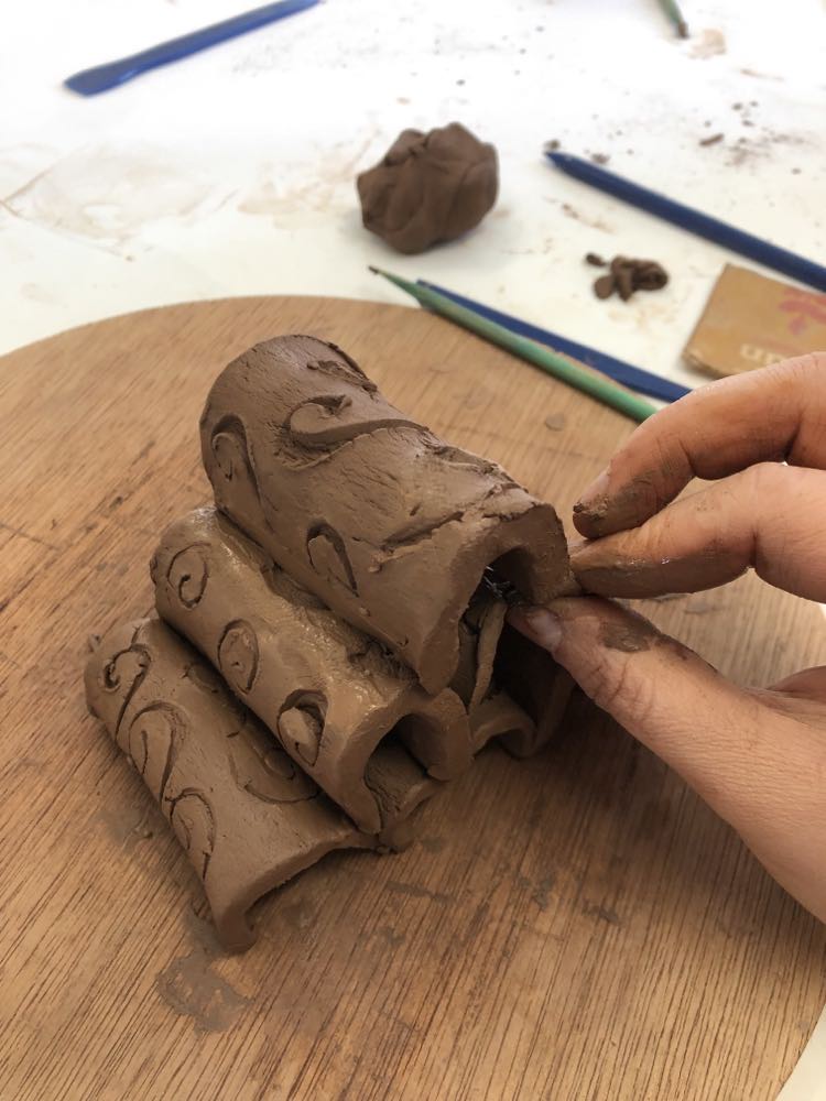 soft clay tiles bent double to produce a rounded spine. stacked on top of each other to make an 'M' shaped sculpture. Bit like rounded barn roofs