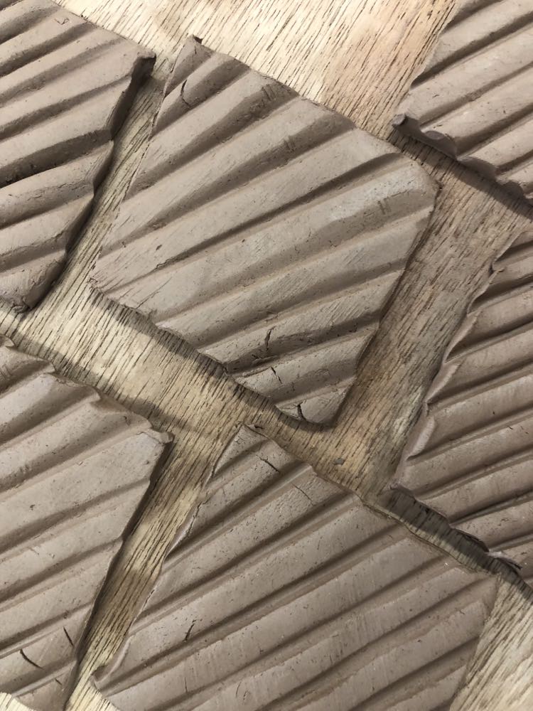 five square clay tiles with pressed diagonal lines to create geometric texture