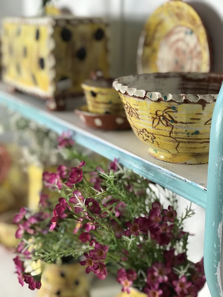 Yellow sgraffito pottery by Sarah monk Ceramics displayed on a shelf at Eastnor Pottery
