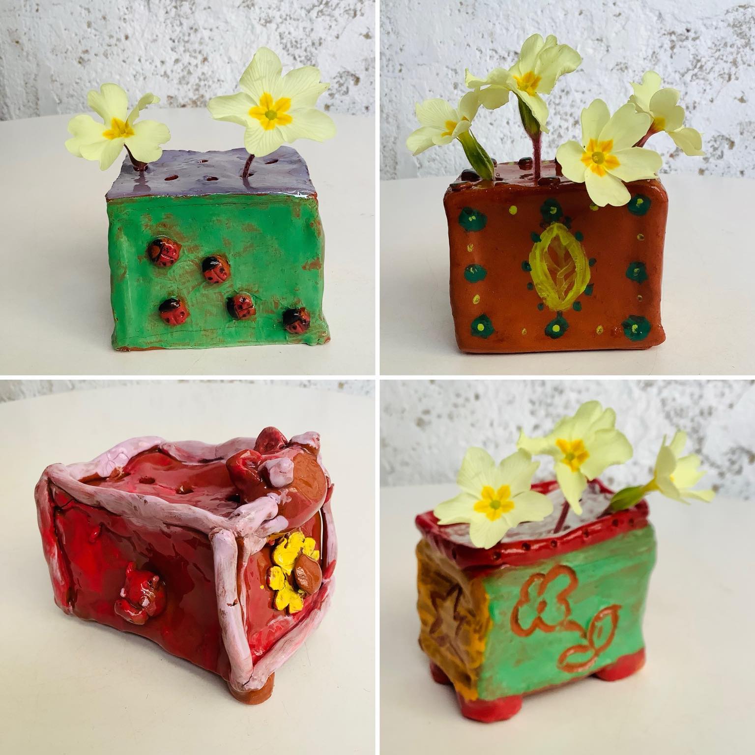composite image of x4 ceramic cubed flower bricks made on a family pottery workshop at eastnor pottery. Each piece is very different from each other. A variety of colours and design. There are small yellow primroses in some of the bricks.