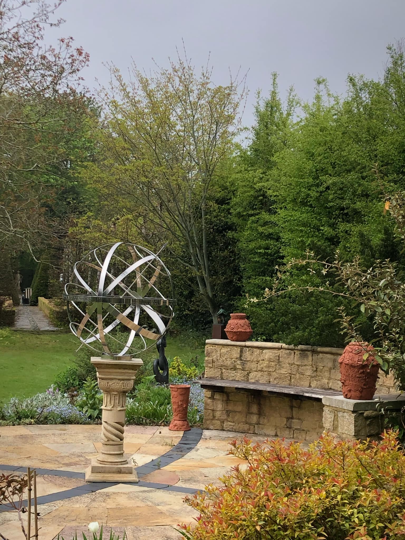 three stunning terracotta coil pots made by children from four banbury schools. the pots are displayed on a cotswold stone patio in the sculpture exhibition at kingham lodges in the cotswolds