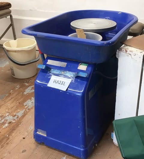 A blue electric pottery wheel labelled on the front with a hand written name Hazel.