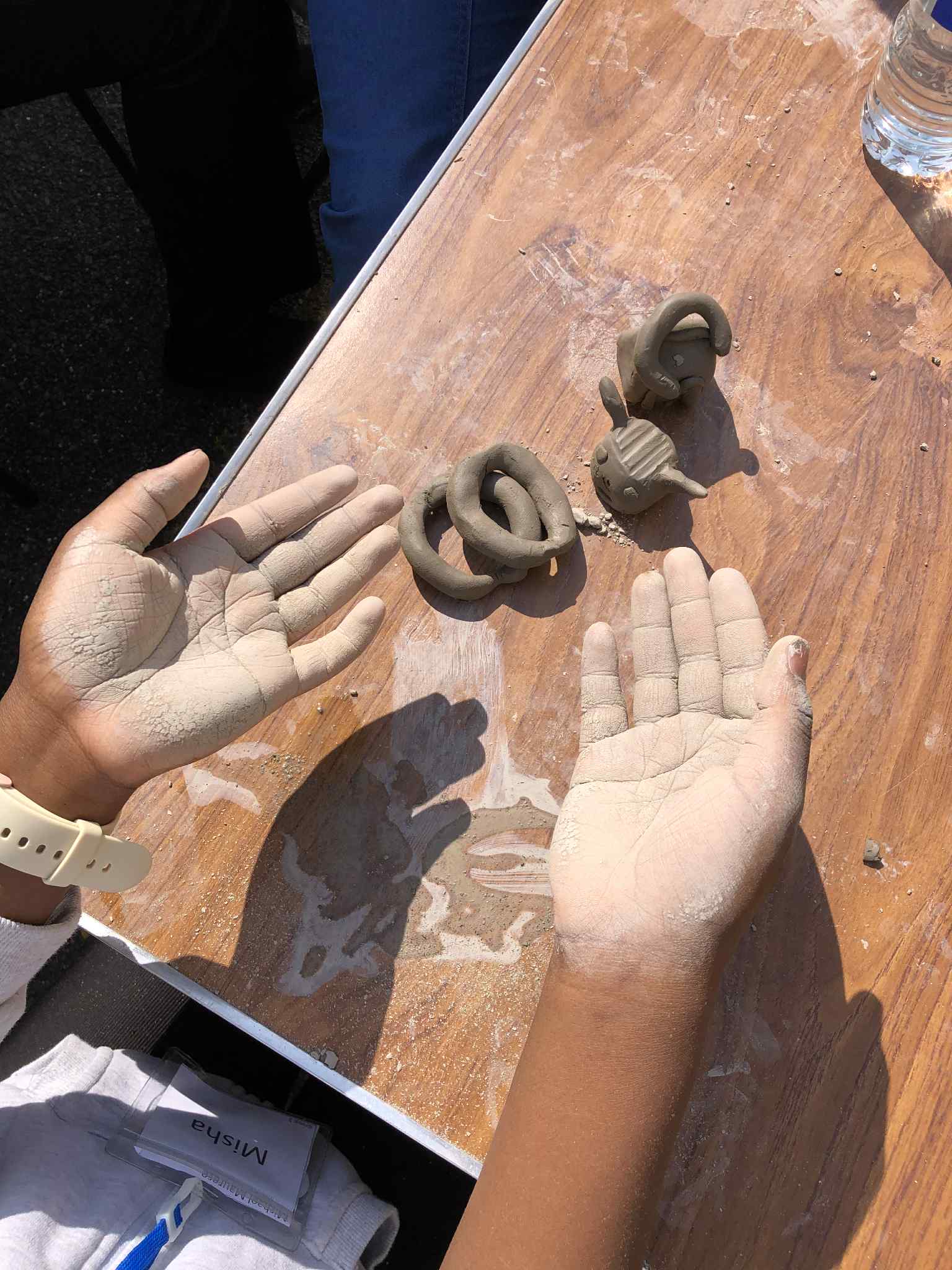 young persons hands palm-up covered in clay dust from modelling clay on the table