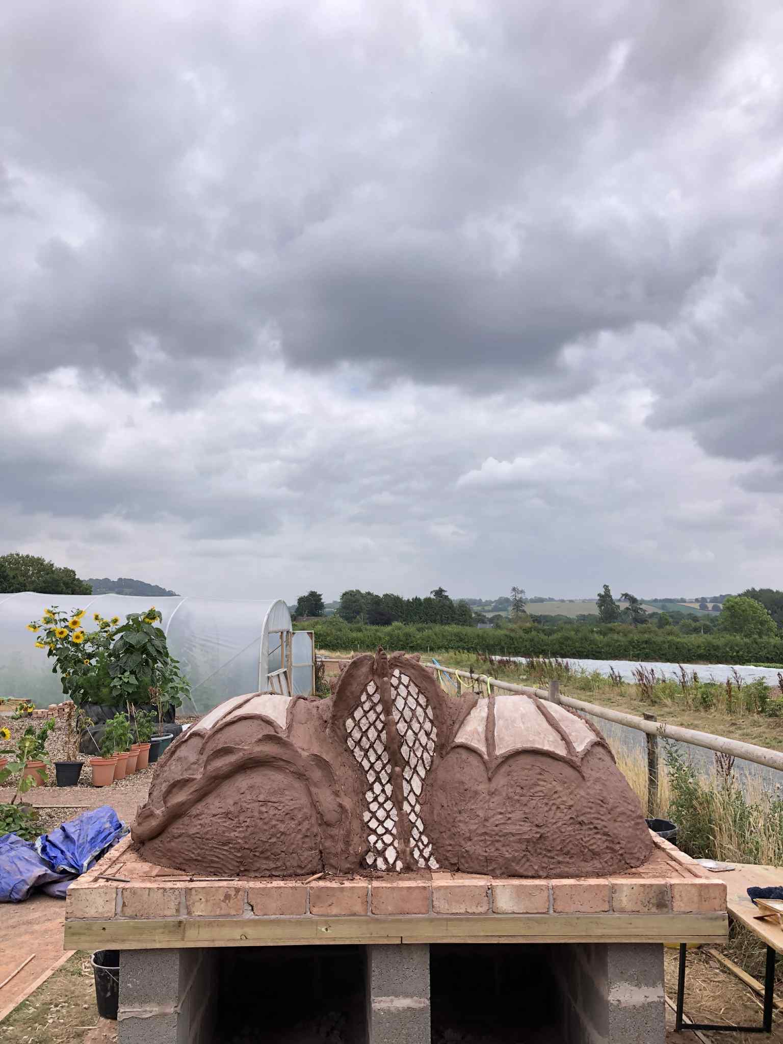 back of cob pizza oven in the shape of dragon wings each one spread over the mounds of the two cooking chambers in the shape of mounds