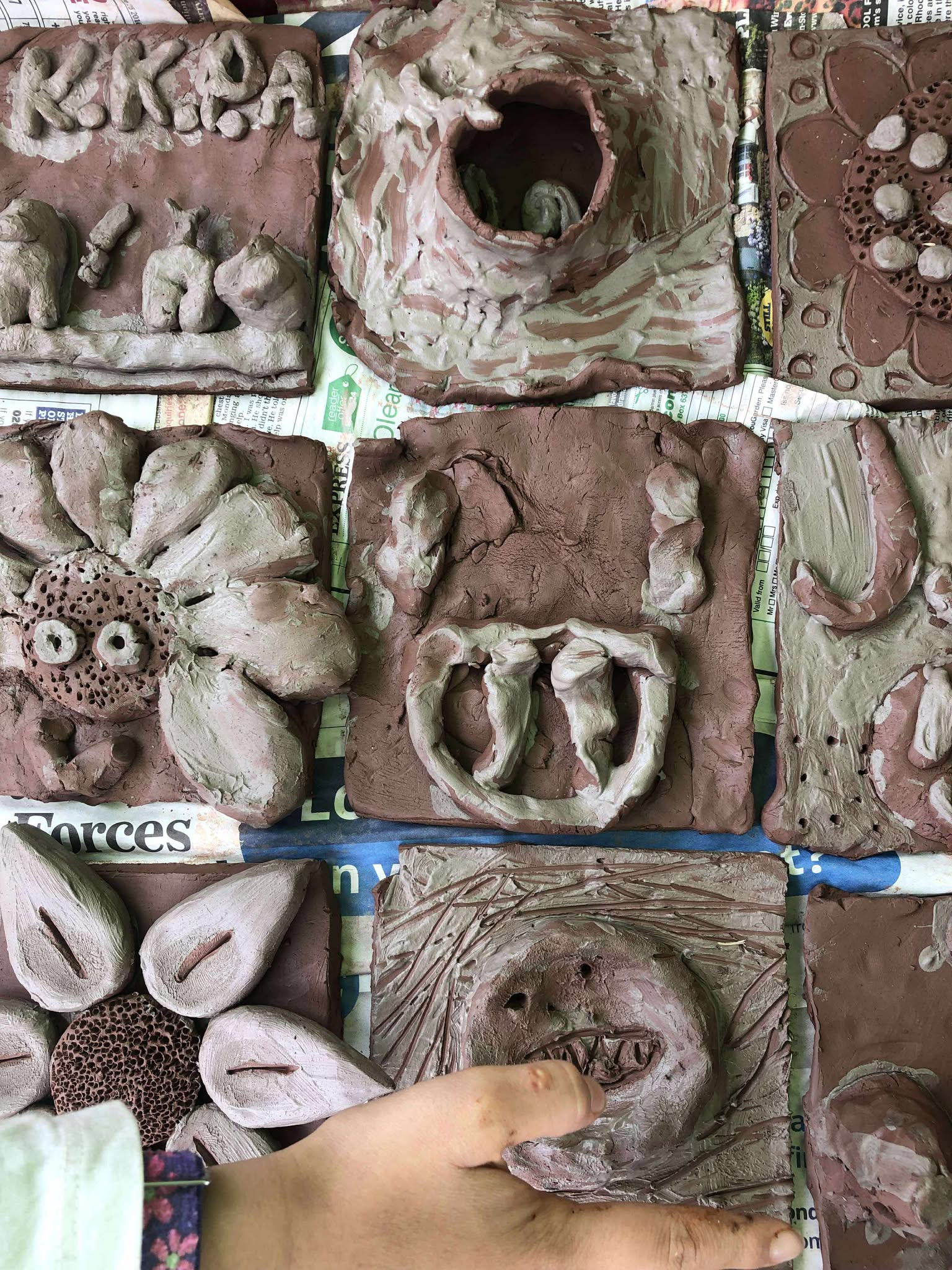 x9 children's clay tiles. brown clay painted with white slip. square tiles closely next to each other like a patchwork.