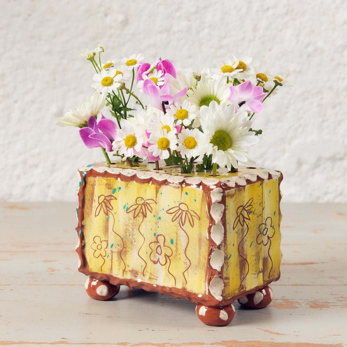 Yellow pottery flower brick made by Sarah Monk with brown etched flowers, white edging and round feet.
