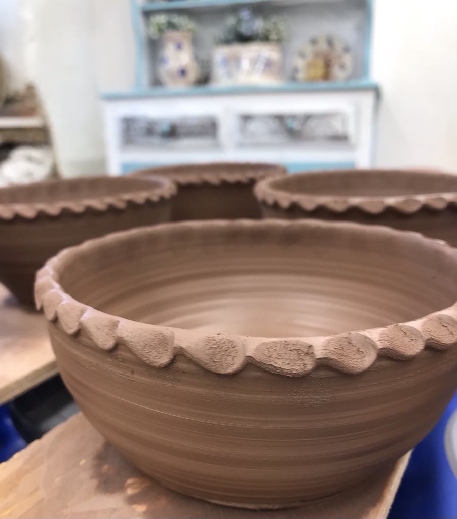 Freshly thrown terracotta bowls with a pie crust rim.