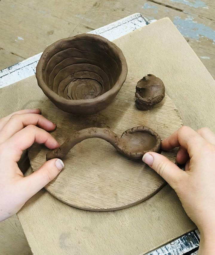 Hands making a clay spoon