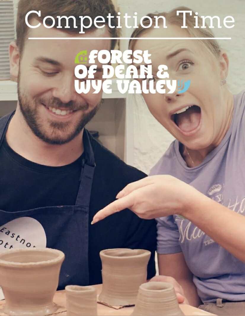 head and shoulders portrait of two happy people male and female pointing and looking at their pottery they have made on the potter's wheel on a pottery course at eastnor pottery herefordshire.