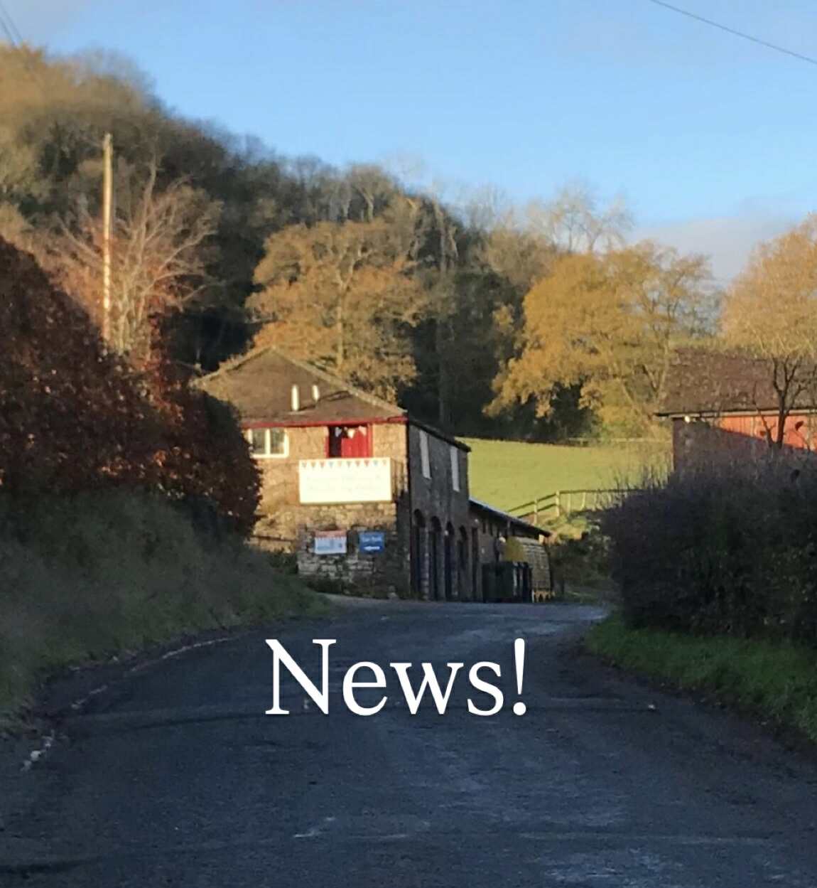 long shot landscape image of eastnor pottery basking in the winter morning sun. The photo shows the pottery building side elivation with a hill, line of trees and blues sky behind the pottery building