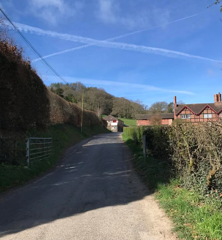 A distant view of Eastnor Pottery At the end of a country  lane lined with hedges.