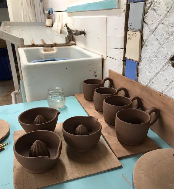 four green ware mugs and three jucers waiting to be decorated.