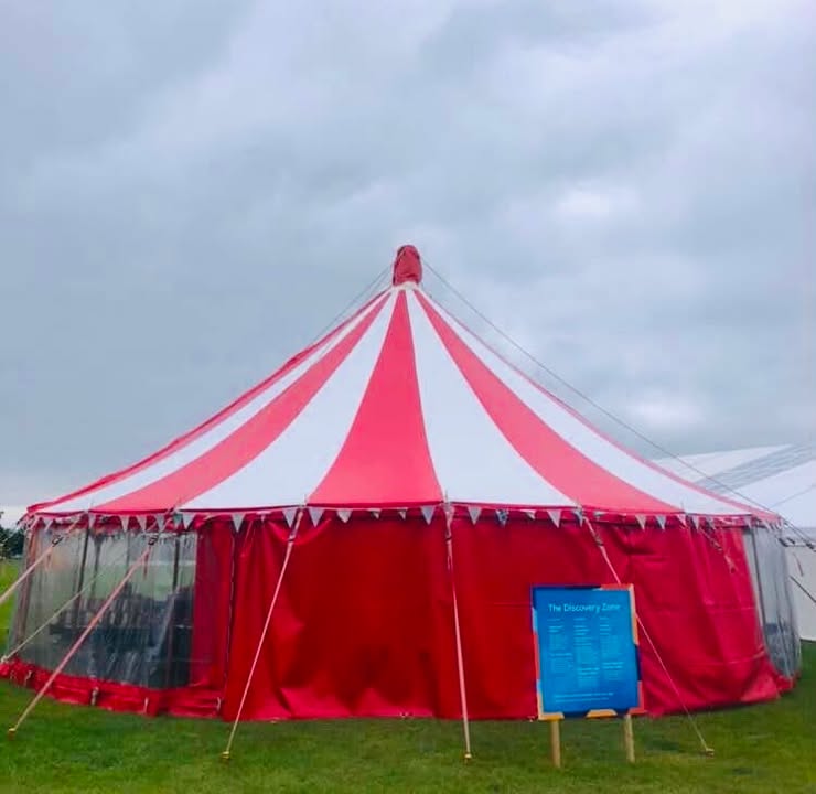 The Discovery Zone tent from the outside. A cicular red and white striped circus tent.