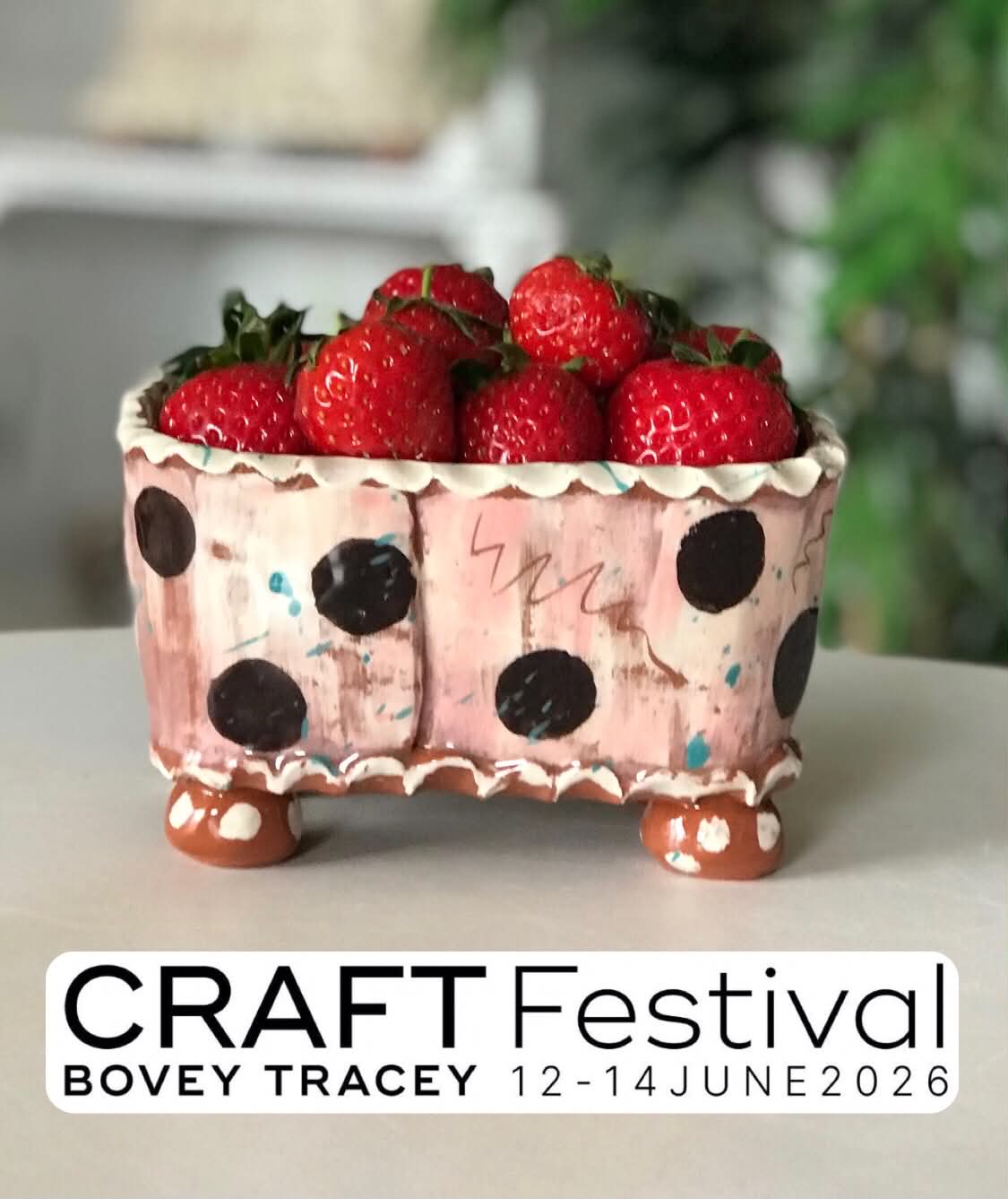 A pink dotty pottery fruit punnet containing fresh strawberries.