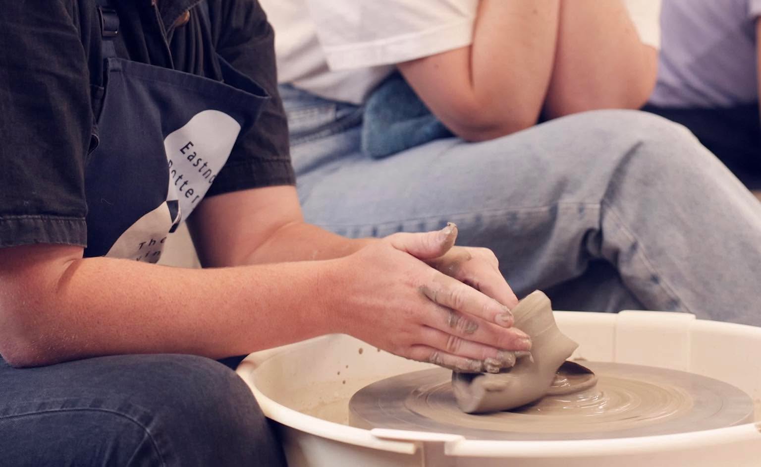 Hands on a  squashed pot on a potter's wheel.